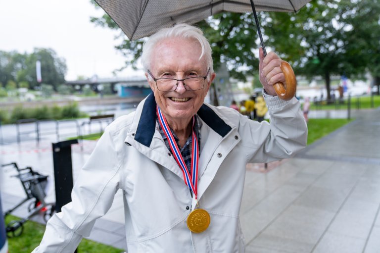 Eldre mann smiler til kamera etter å ha fått medalje for deltakelse på Generasjonslekene