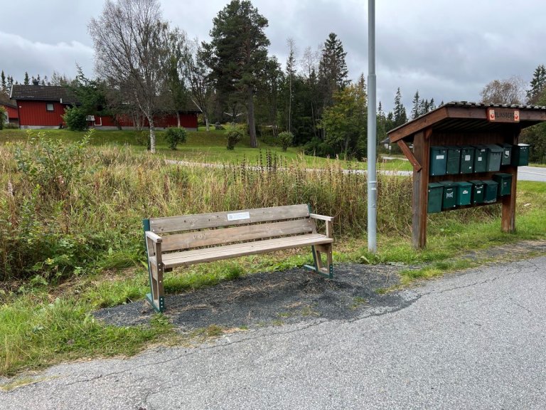 En benk som står i nærheten av et postkassestativ