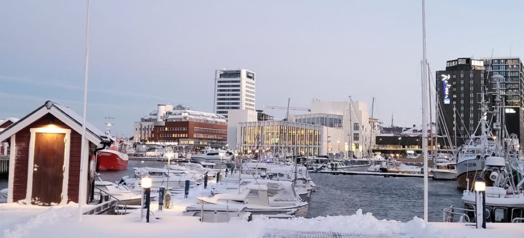 En marina dekt i snø med skyline av en by i bakgrunnen. 